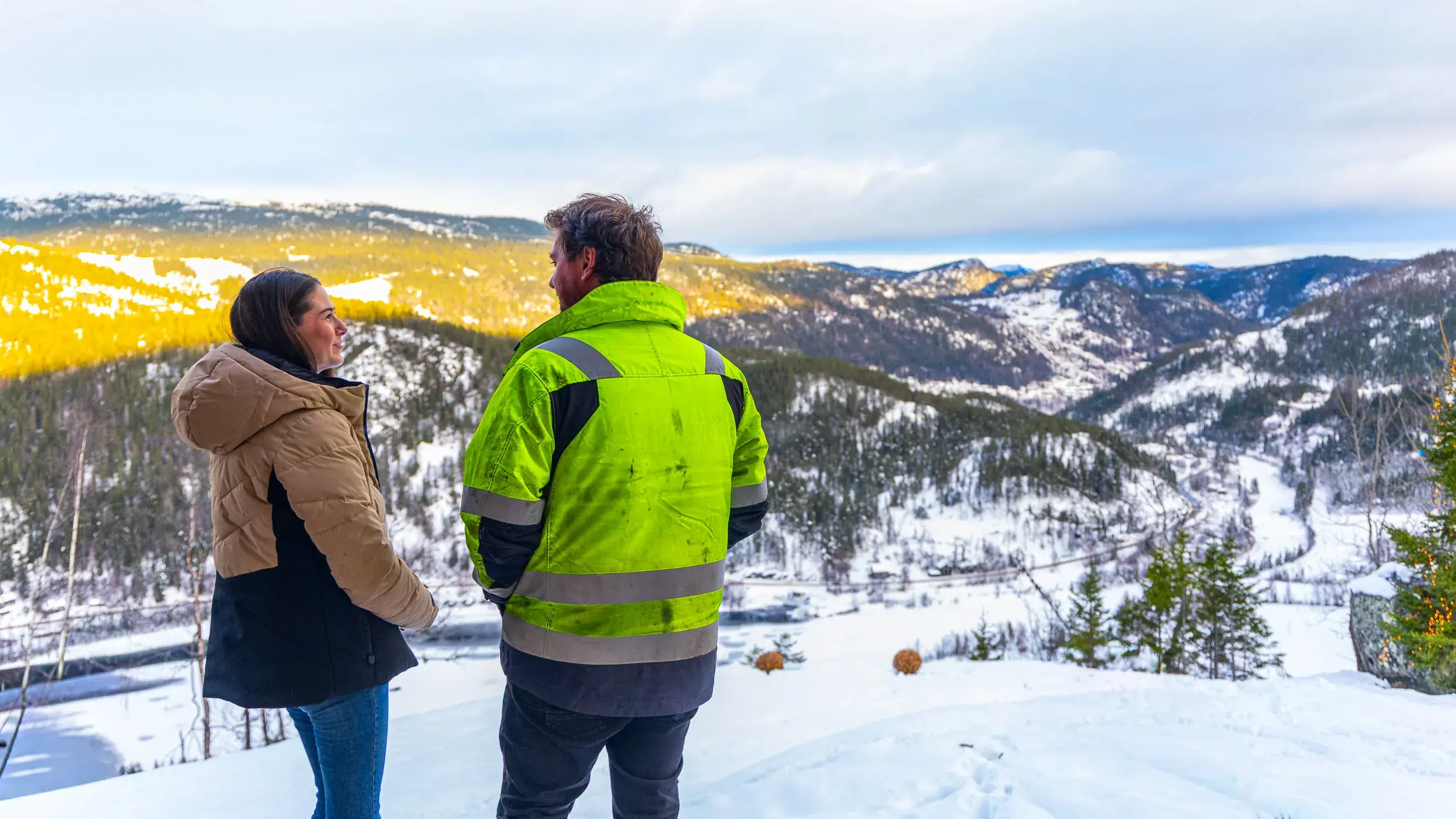 Inge og Carina står i snøen og ser utover dalen fra tomta si i fjellsiden ved Rødberg