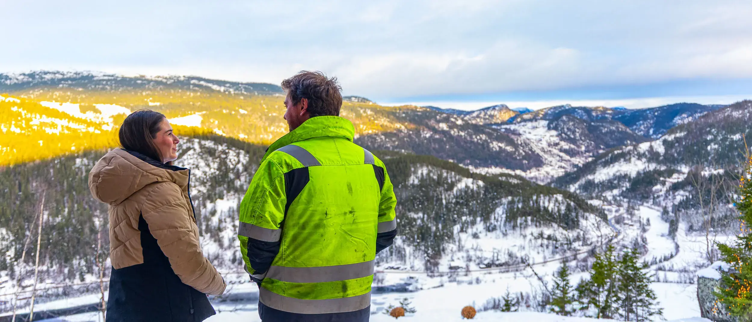 Inge og Carina står i snøen og ser utover dalen fra tomta si i fjellsiden ved Rødberg