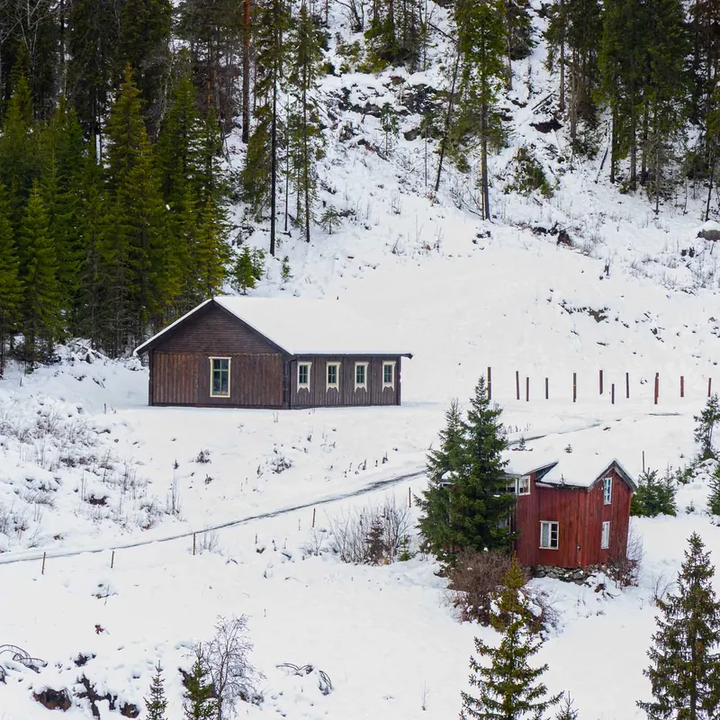 Et nytt hus og en stall i snøen i fjellsiden ved Rødberg